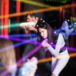 girl in colored beams during laser tag game
